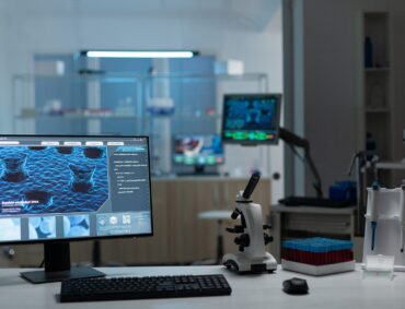 Computer with microbiology virus expertise on display standing on table during biochemistry experiment in biological hospital laboratory. Healthcare treatment development